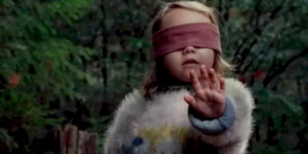 Dievča s rukou hore smerom k tvorom v Bird Box