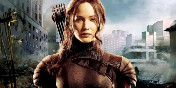 Jennifer Lawrence jako Katniss Everdeen na pozadí Kapitolu ve franšíze Hunger Games.