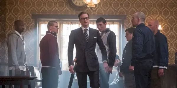 Harry Heart går inn på en pub omgitt av mennesker i Kingsman: The Secret Service.