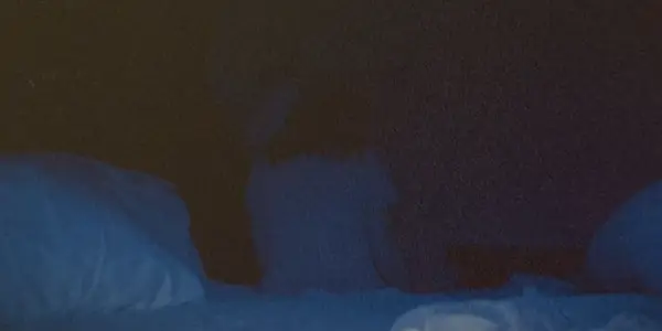 Žena sedí na posteli čelem ke zdi ve Skinamarinku
