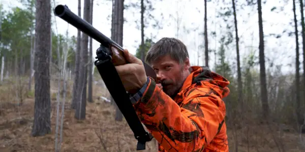 Nikolaj Coster-Waldau segura um rifle de caça enquanto interpreta Rayburn em The Silencing.