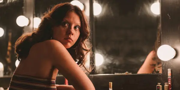 Maxine (Mia Goth) mira por encima del hombro mientras está sentada frente a un tocador en su camerino en X.