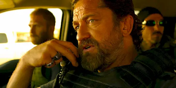 Gerard Butler parla alla radio mentre viaggia in macchina in una scena di Den of Thieves