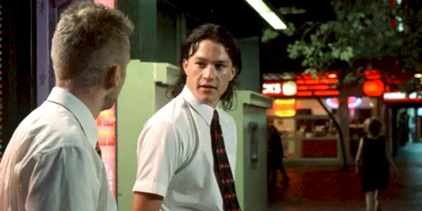 Heath Ledger rozmawia na zewnątrz, mając na sobie koszulę i krawat.