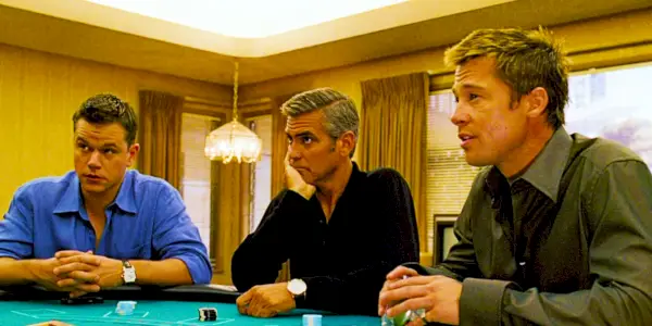 Matt Damon nei panni di Linus Brad Pitt nei panni di Rusty e George Clooney nei panni di Danny seduti al tavolo da gioco in Ocean