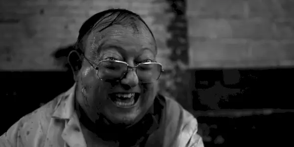 Laurence R. Harvey som Martin Lomax smiler manisk i The Human Centipede 2