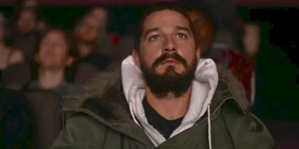 Shia LaBeouf sitzt in einer Menschenmenge.