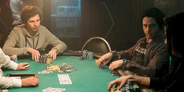 Hráč X sedí u pokerového stolu se dvěma dalšími hráči z Molly