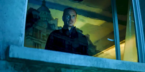 Michael Fassbender sa pozerá cez okno v The Killer
