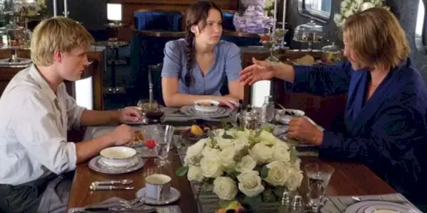 Peeta, Katniss a Haymitch mluví u stolu ve vlaku v Hunger Games