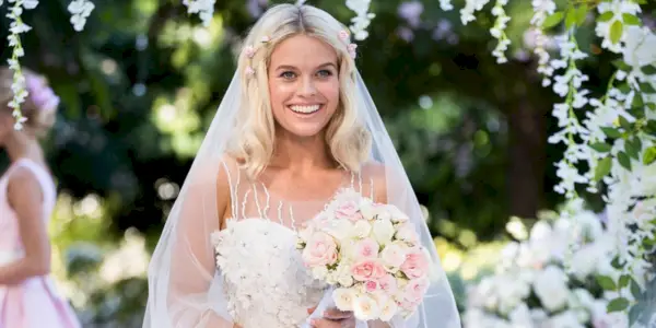 Alice Eve se široce usmívá, když stojí ve svatebních šatech a drží kytici v epizodě Black Mirror