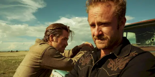 Ben Foster sieht besorgt aus, mit Chris Pine im Hintergrund, der sich in Hell or High Water an einen Lastwagen lehnt.