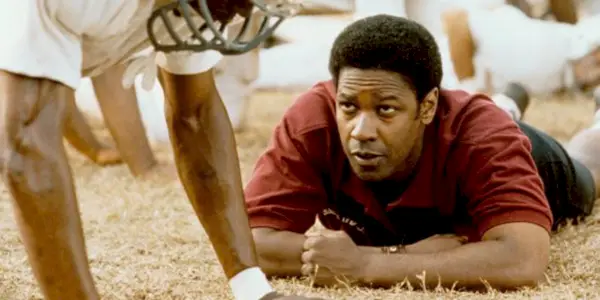 Denzel Washington ligger på jorden og kigger på en spiller i Remember The Titans