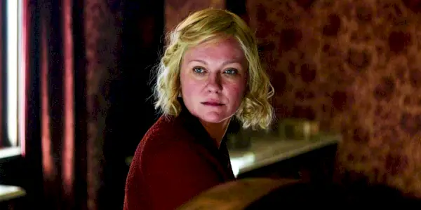 Kirsten Dunst jako Rose Gordon siedzi w czerwonym pokoju w swetrze w Mocy psa