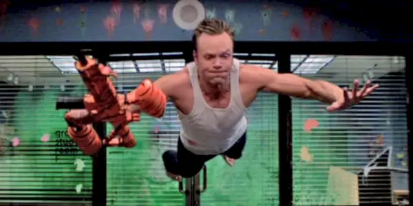 Joel McHale pulando de uma explosão de paintball em Community