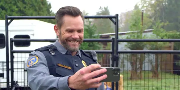 Joel McHale enquanto Frank sorri e tira uma foto no Animal Control