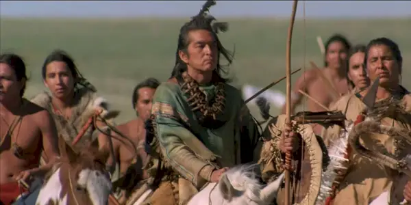 Tento obrázok zobrazuje ľudí z národa Lakota, ktorí jazdia na koňoch a držia zbrane.