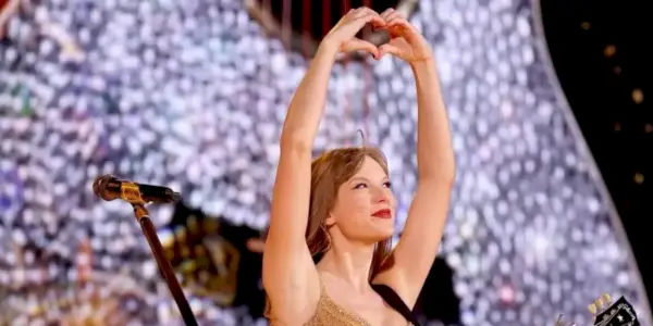 Taylor Swift lager formen til et hjerte med hendene mens hun opptrer på Eras Tour
