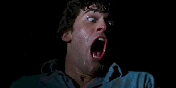 Bruce Campbell jako Ash křičící do tmy ve filmu The Evil Dead (1981) od Sama Raimiho