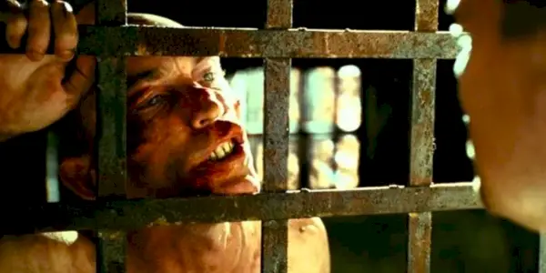 George Noyce appoggiato alle sbarre di una prigione a Shutter Island