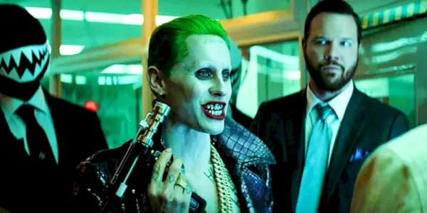 Joker holder et verktøy mens han snakker med noen og flankert av vakter i Suicide Squad