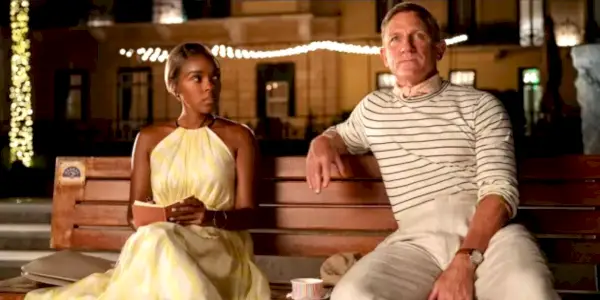 Helen (Janelle Monáe) et Benoit (Daniel Craig) assis ensemble sur un banc dans Glass Onion : A Knives Out Mystery.