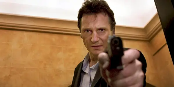Liam Neeson punta una pistola verso la telecamera in Taken
