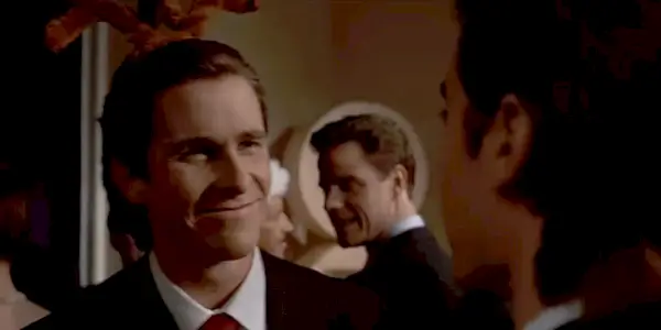 Patrick zmusza się do uśmiechu w American Psycho