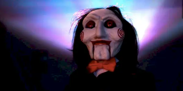 Billy die Puppe mit Licht hinter sich in der Saw X-Parodie der Nicole Kidman AMC-Werbung
