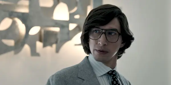 Maurizio Gucci con gafas y mirando a su lado en House of Gucci.