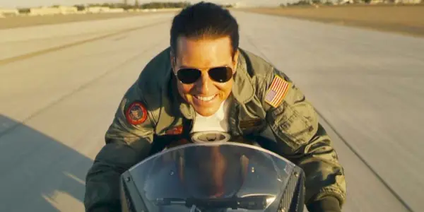 Tom Cruise sonriendo mientras conduce una motocicleta en Top Gun: Maverick