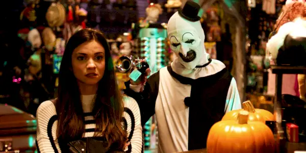 Art the Clown parado atrás de Sienna em uma loja em Terrifier 2