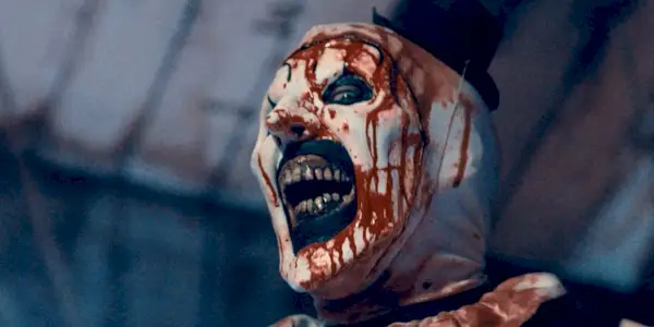 Art the Clown sorrindo com o rosto ensanguentado em Terrifier 2