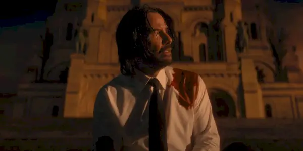 John Wick (Keanu Reeves) senta-se nos degraus no final de John Wick Capítulo 4