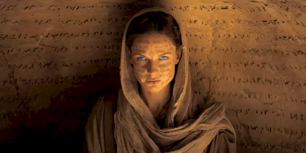 Lady Jessica olhando para a câmera com texto em todo o rosto e na parede em Duna (2021).