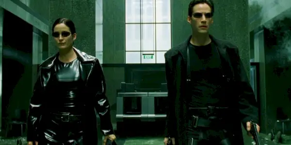 Carrie-Anne Moss som Trinity og Keanu Reeves som Neo går mens de er ekstremt godt bevæpnet før hun reddet Laurence Fishburne som Morpheus i The Matrix