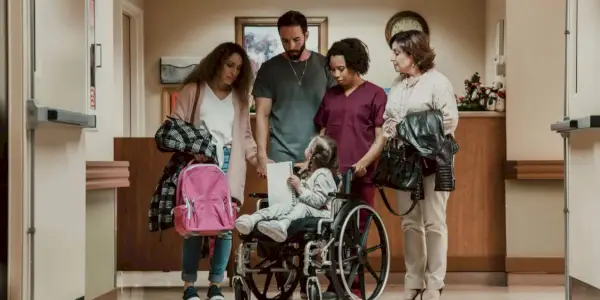 לוסי שימרס יושבת על כיסא גלגלים ומסתכלת אחורה על הוריה ואחיותיה בבית החולים בלוסי שימרס ונסיך השלום