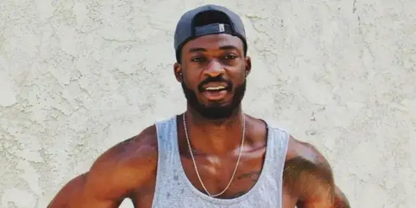 Dotun Olubeko The Bachelorette portant un débardeur et une casquette de baseball souriant