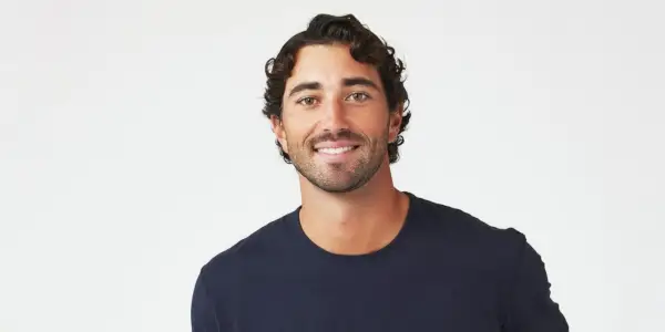 Joey Graziadei The Bachelorette Promo Photo v modré košili a bílém pozadí