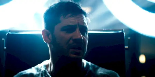 Eddie Brock siedzący pod jasnym światłem przesłuchań w Venom.