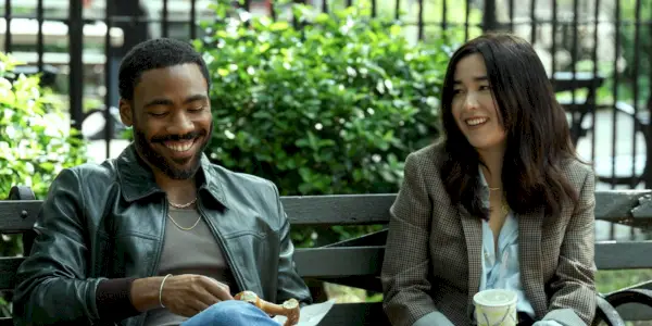 Donald Glover als John und Maya Erskine als Jane lachend auf einer Bank in Mr. & Mrs. Smith