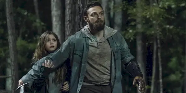 Aaron z The Walking Dead vyzerá vystrašene a chráni Gracie, ktorá je za ním.