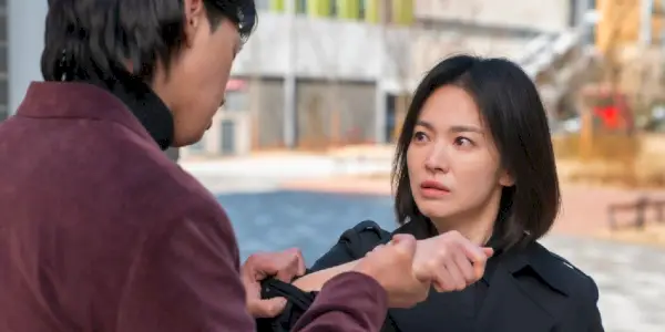 Dong-eun (Song Hye-kyo) vypadá vyděšeně, když ji někdo chytne za zápěstí v The Glory