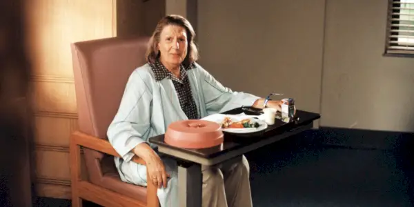 Nancy Marchand como Livia Soprano sentada frente a una mesa con comida