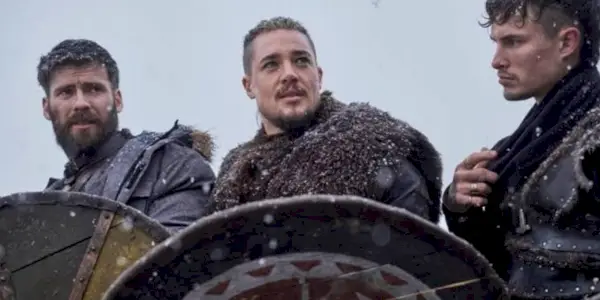 Alexander Dreymon dans le rôle d'Uhtred debout avec ses hommes portant des boucliers dans The Last Kingdom