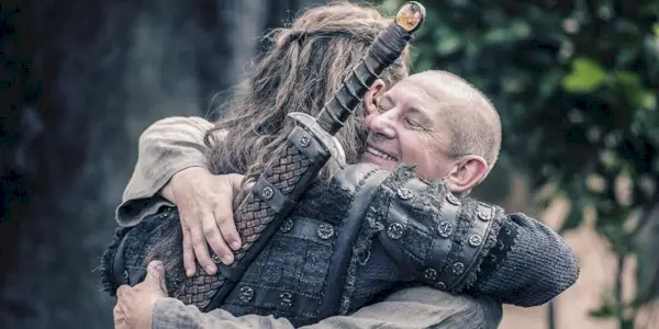 Une image d'Alexander Dreymon dans le rôle d'Uhted et de Ian Hart dans le rôle de Beocca s'enlaçant dans The Last Kingdom