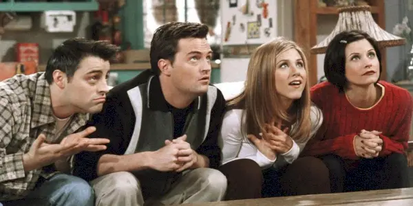 Uma imagem de Chandler, Joey, Rachel e Monica olhando com entusiasmo para Ross em Friends
