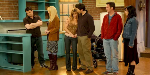 Uma imagem de todos os seis personagens de Friends parados na cozinha