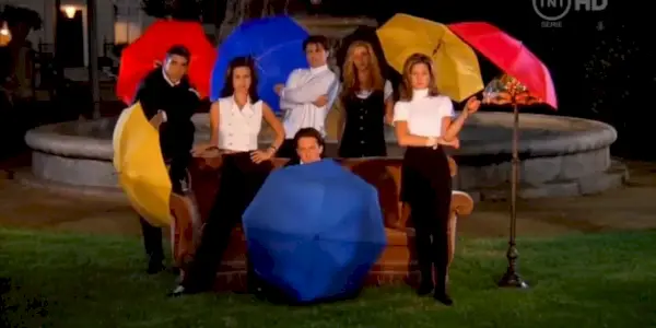Uma imagem dos seis personagens principais segurando guarda-chuvas de Friends