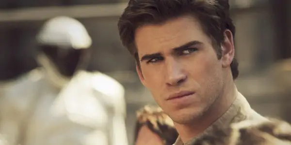 Gale Hawthorne (Liam Hemsworth) parece intenso com Peacekeepers ao fundo em Jogos Vorazes.